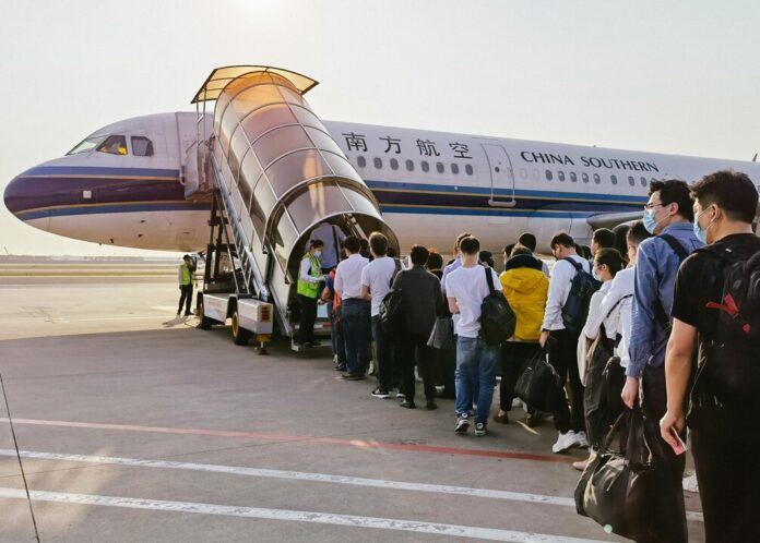 Passengers queue in line for boarding under the plane